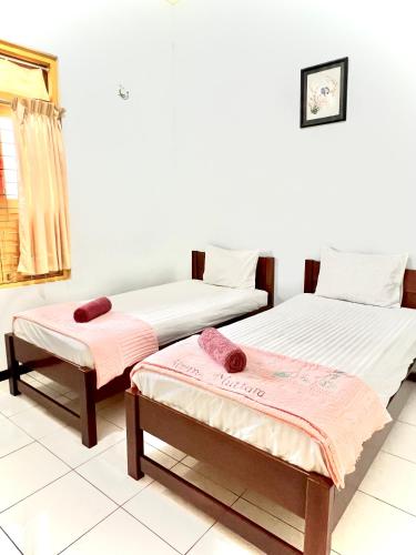 two beds in a room with towels on them at Wisma Mutiara in Padang