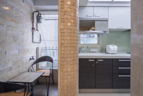 a kitchen with a table and chairs and a brick wall at Comfy & Central 2B1b, Sleeps 5, 3min to Daan MRT 舒適市中心 2房1衛 睡5人 3分到大安站 in Taipei