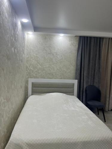 1 dormitorio con 1 cama blanca y 1 silla en Surami, en Surami