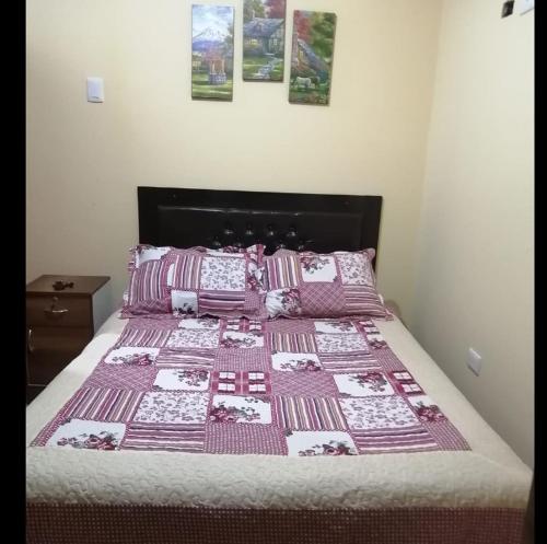 un letto con una trapunta rosa e bianca sopra di ANDINOS DEL COLCA a Chivay