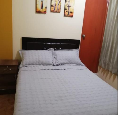 un letto con lenzuola e cuscini bianchi in una camera da letto di ANDINOS DEL COLCA a Chivay
