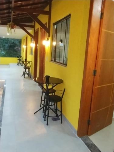 uma fila de mesas e cadeiras numa sala com paredes amarelas em Hospedagem Encantos da Serra em Itatiaia