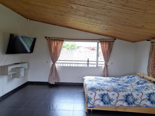 a bedroom with a bed and a tv and a window at Reserva de Santa Ines Valle de Tibasosa in Tibasosa