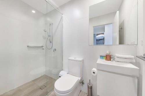 a white bathroom with a toilet and a shower at Sydney Homebush Two bedroom Apartment with 2 Parkings in Sydney