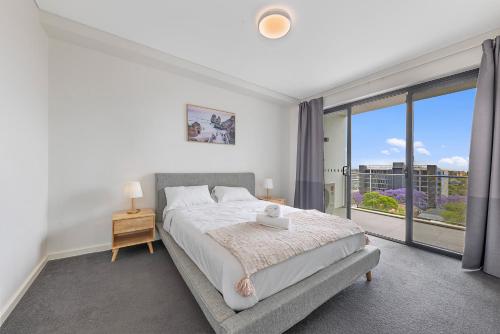 a bedroom with a bed and a large window at Sydney Homebush Two bedroom Apartment with 2 Parkings in Sydney