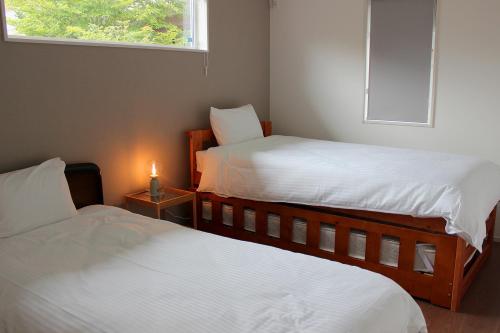 2 Betten in einem kleinen Zimmer mit einer Kerze auf dem Tisch in der Unterkunft IZUMIYA2 in Shin-karuisawa