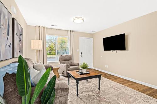 a living room with a couch and a tv on a wall at Newly Renovated Flat near Downtown Roseville in Roseville