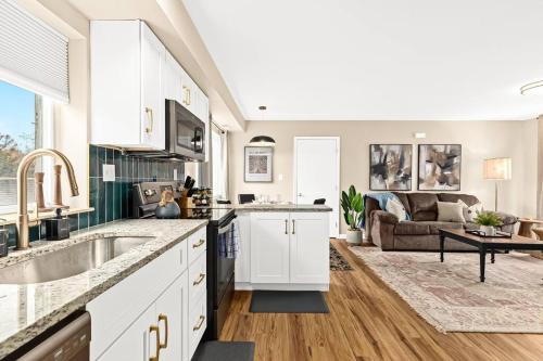 a kitchen with white cabinets and a living room at Newly Renovated Flat near Downtown Roseville in Roseville