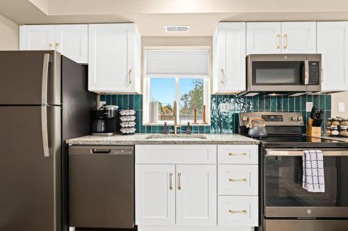 a kitchen with white cabinets and a black refrigerator at Newly Renovated Flat near Downtown Roseville in Roseville