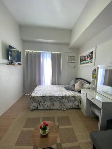 een slaapkamer met een bed, een bureau en een tafel bij Eve's Condo in Cagayan de Oro