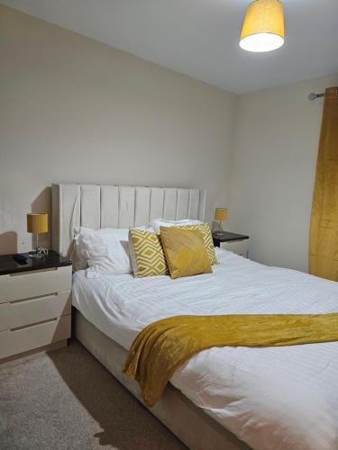 a bedroom with a large white bed with yellow pillows at Waterfront, Ethihad stadium apartments in Manchester