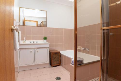 a bathroom with a tub and a sink and a mirror at McKinnon on the Bay in East Ballina