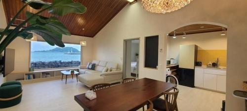 a living room with a couch and a table and a kitchen at Hey Day Jeju in Jeju