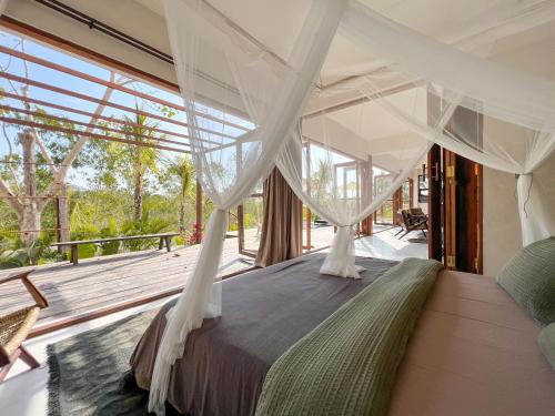 a bedroom with a canopy bed with a large window at Nowhere Villa Uluwatu in Uluwatu