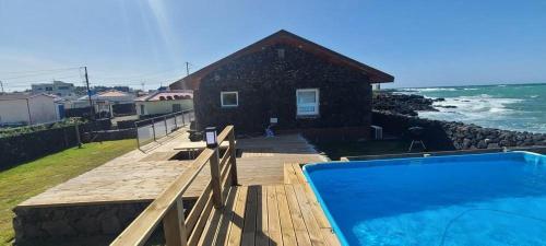 a house with a swimming pool next to the ocean at Hey Day Jeju in Jeju