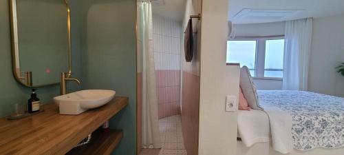 a bathroom with a bed and a sink and a mirror at Hey Day Jeju in Jeju