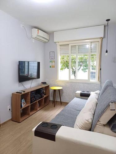 ein Wohnzimmer mit einem Sofa und einem TV in der Unterkunft Apto. Térreo Perto do Consulado in Porto Alegre