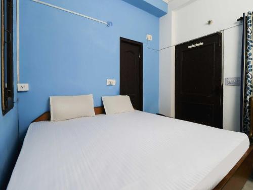 a bedroom with a large white bed with blue walls at OYO 48765 Hotel Amandeep in Ludhiana