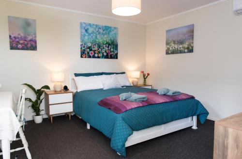 a bedroom with a bed and two paintings on the wall at Hopwood Bed & Breakfast in Taihape