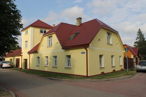 una casa amarilla con techo rojo en una calle en Amrai, en Ventspils