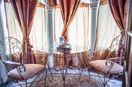 una mesa de cristal y 2 sillas en una habitación con cortinas en The Anniversary Inn - South Temple, en Salt Lake City