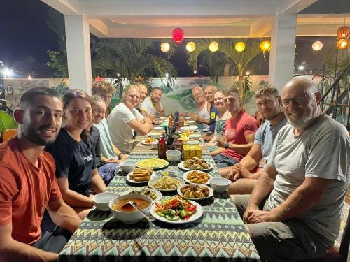 grupa ludzi siedzących przy stole z jedzeniem w obiekcie YoLo Pool Bar Villas w mieście Phong Nha