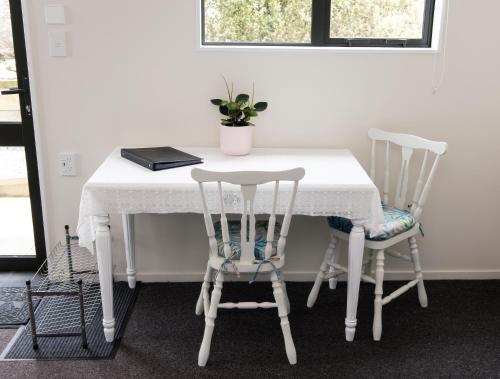 een witte tafel met twee stoelen en een laptop erop bij Hopwood Bed & Breakfast in Taihape