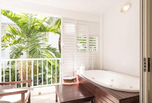 a bathroom with a tub and a palm tree at Couple's Coastal Haven Retreat at The Beach Club in Palm Cove