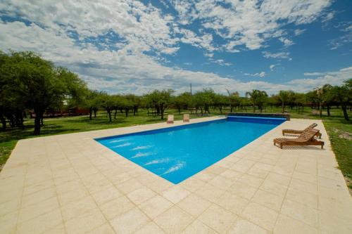 una piscina con 2 salones y 2 sillas al lado en Cabañas del Viñedo en La Paz