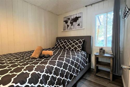 um quarto com uma cama em preto e branco e uma janela em Le1601 - Le Petit Renard - Chalet spa et plage em Sainte-Lucie-de-Doncaster
