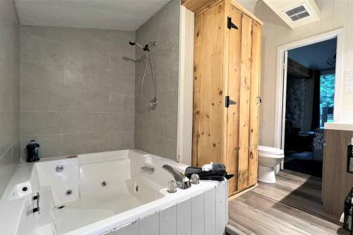 uma grande banheira branca na casa de banho em Le1601 - Le Petit Renard - Chalet spa et plage em Sainte-Lucie-de-Doncaster