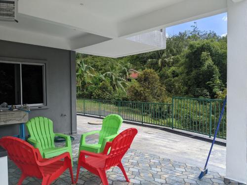 three red and green chairs sitting on a porch at Villa with Titiwangsa Hill View in Kerling