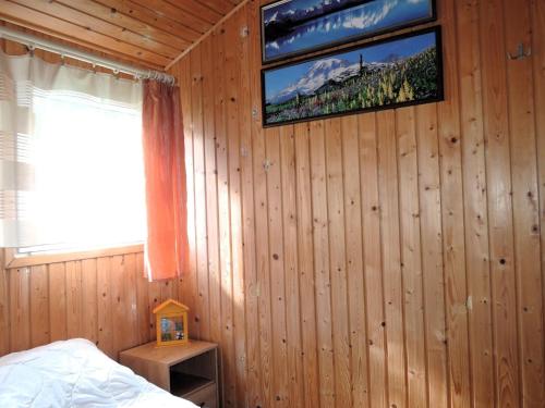 a bedroom with a tv on a wooden wall at Bungalow with terrace, Wrzosowo in Wrzosowo