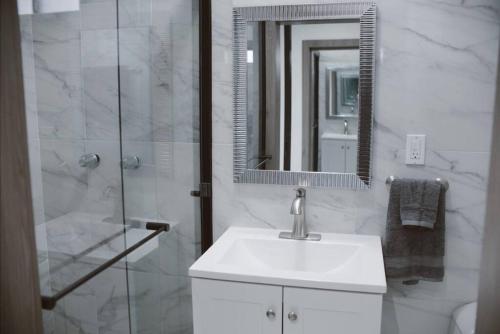 a bathroom with a sink and a shower with a mirror at Macfarland Suites in Ensenada