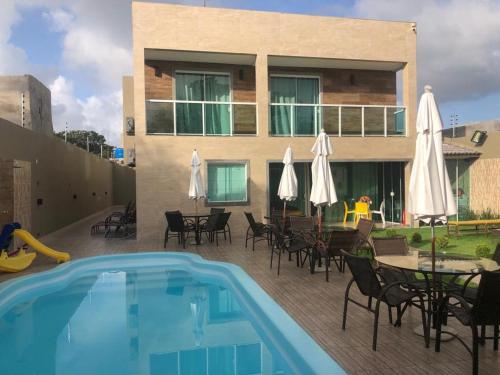 a patio with a pool and tables and umbrellas at LINDA CASA BARRA DE JACUIPE 8/4 ACOMODA ATE 20 PESSOAS in Camaçari