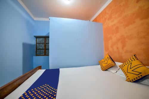 - une chambre dotée d'un lit avec des draps jaunes et bleus dans l'établissement SPOT ON Shashi Prabha Palace, à Deoghar
