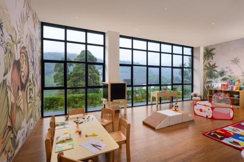 una sala de estar con mesas y sillas y una gran ventana en The Golden Ridge Hotel, en Nuwara Eliya