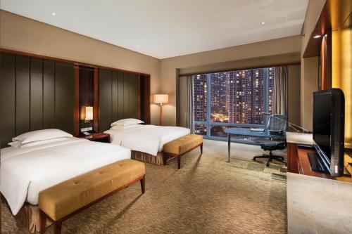 Hilton Nanjing Riverside في نانجينغ: غرفة فندقية بسريرين ومكتب وتلفزيون