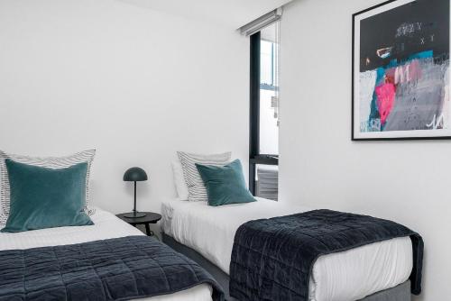 Duas camas num quarto branco com almofadas verdes em Boutique Stays - Axel Apartments G02 The Faircroft em Melbourne