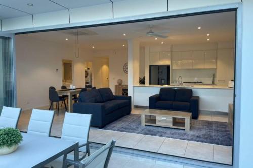 a living room with two blue couches and a kitchen at Inner City Stay Mildura in Mildura