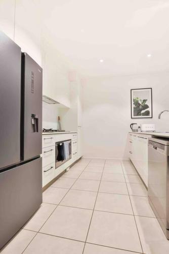 a kitchen with white appliances and white tile floors at Inner City Stay Mildura in Mildura