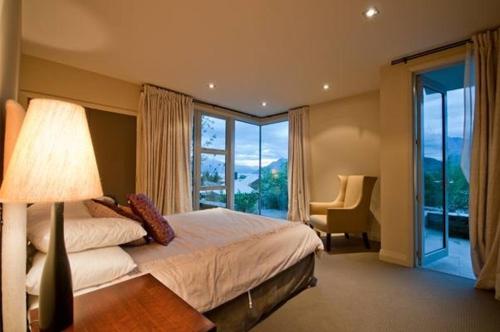 a bedroom with a bed with a lamp and a window at Rangatira at 13 Poole lane in Queenstown