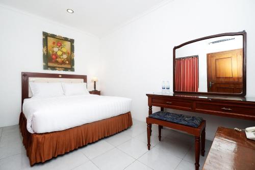 una camera con letto e comò con specchio di Perdana Kasih Hotel Klaten a Solo