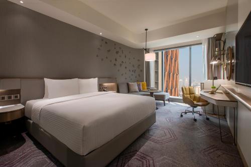 um quarto com uma grande cama branca e uma secretária e um quarto com uma janela em Crowne Plaza Kuala Lumpur City Centre, an IHG Hotel em Kuala Lumpur