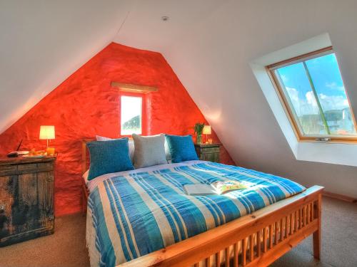 a bedroom with a bed with a red wall at Rhosson Chapel Cottage in St. Davids