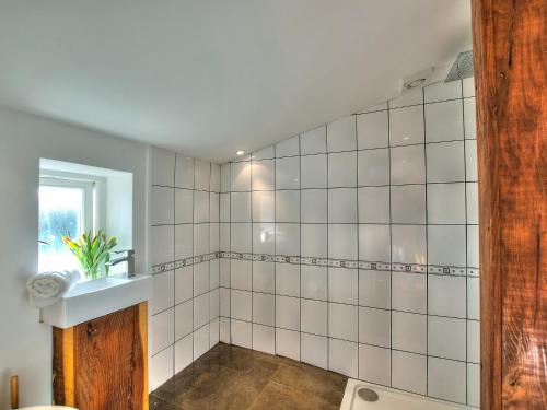 a bathroom with white tiled walls and a sink at Rhosson Chapel Cottage in St. Davids