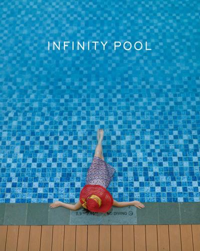 a person laying on the ground in a swimming pool at Marianna Resort And Convention Tuktuk - Samosir, Marclan Collection in Tuk Tuk