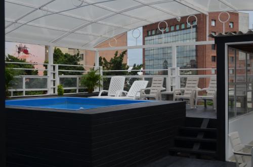 a patio with a hot tub and chairs and a building at Hotel Six Avenue in Cali