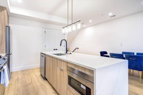 a white kitchen with a sink and blue chairs at Capitol View 3 Penthouse with Rooftop in Washington