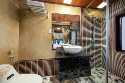 uma casa de banho com um lavatório, 2 espelhos e um WC. em Cozy Bay Classic Cruise em Ha Long